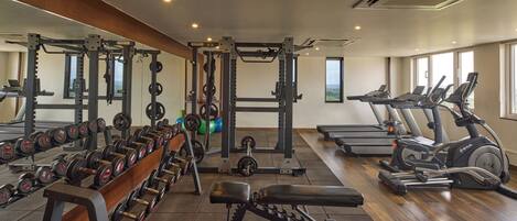 A gym with weightlifting equipment, treadmills, and a bench.