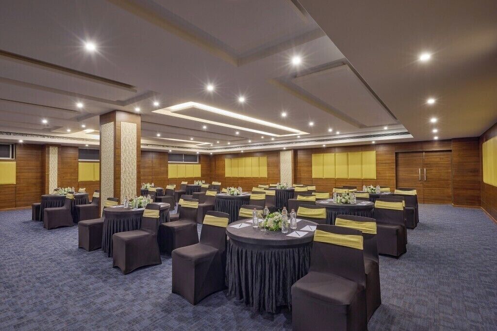 Une salle de conférence dotée de tables rondes et de chaises, ainsi que de plaques nominatives et de bouteilles d’eau.