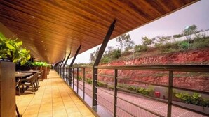 An indoor corridor with a tiled floor, wooden ceiling, and metal railing. - Regenta Hubbali (Hubli)
