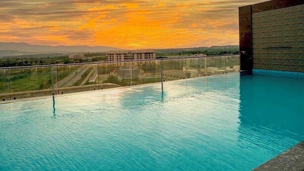 A swimming pool with a clear view of the surrounding landscape and a sunset in the background. - Regenta Hubbali (Hubli)