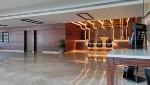 A modern hotel lobby with a reception desk, seating area, and a large digital screen. - Regenta Hubbali (Hubli)