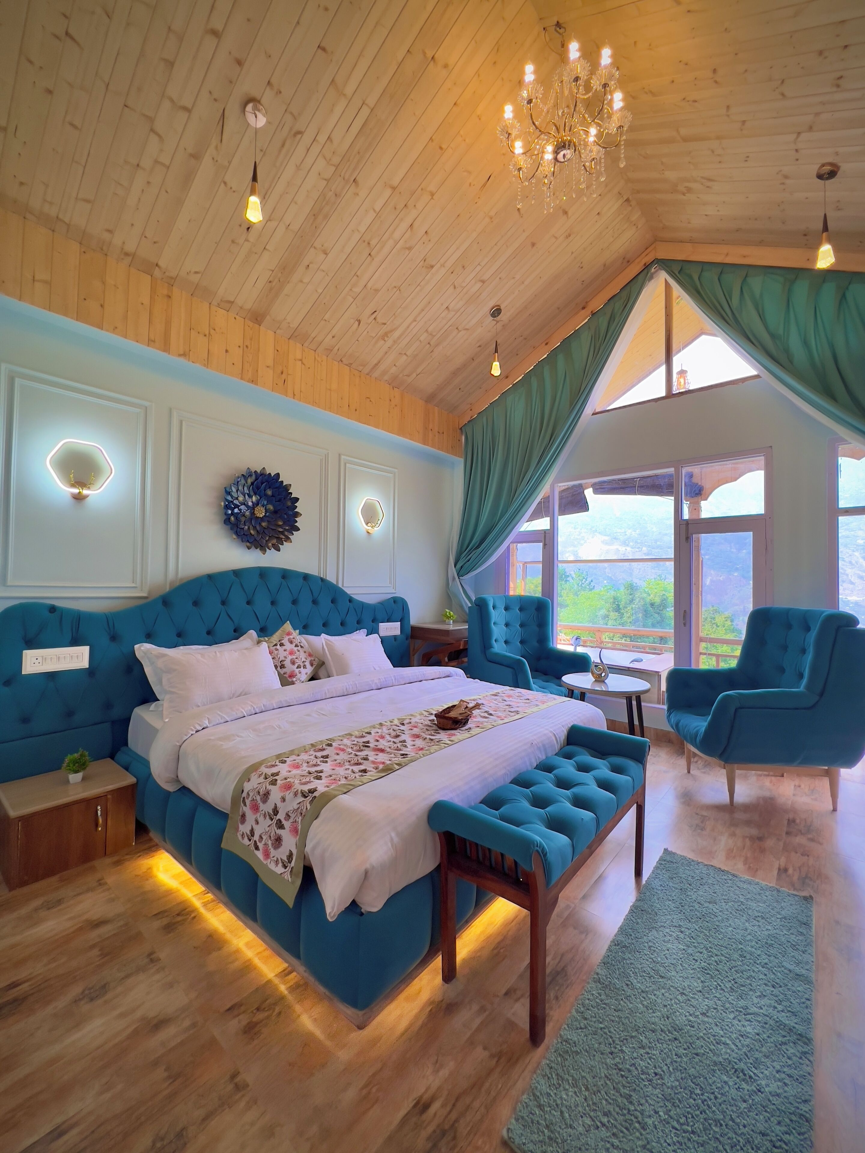 Een slaapkamer met een groot bed, houten plafond en uitzicht op het omliggende landschap.