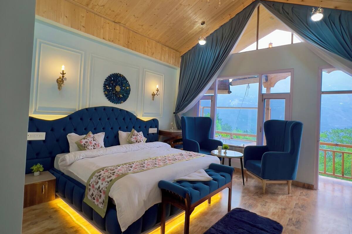 A bedroom with a large bed, a chandelier, and a view of the outdoors.