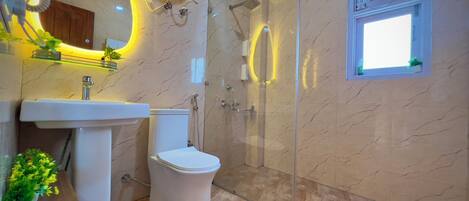 A modern bathroom with a glass-enclosed shower, a white toilet, and a sink with a marble countertop.