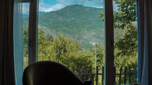 Een kamer met een groot raam met uitzicht op een bergachtig landschap.