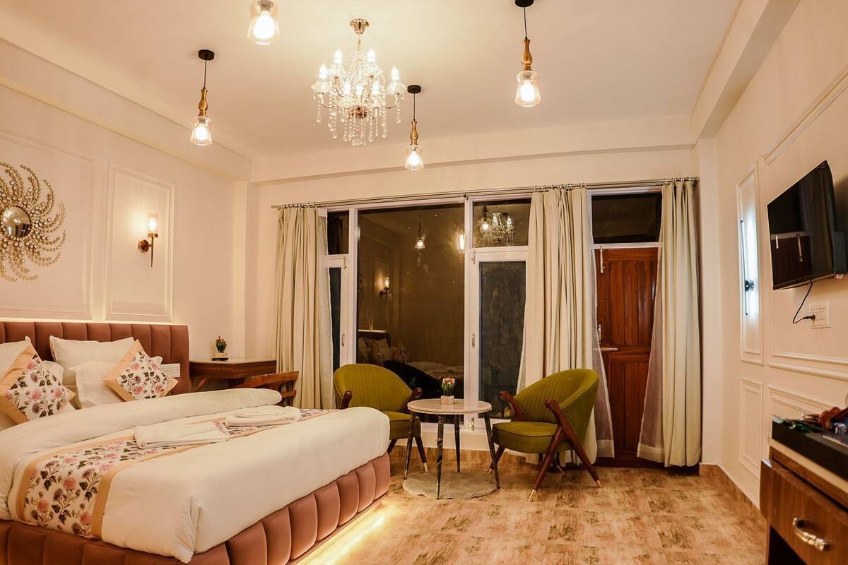 A hotel room with a large bed, a chandelier, a television, and a view of the outside.