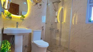 Een moderne badkamer met een douchecabine van glas, een wit wastafelmeubel en een toilet.