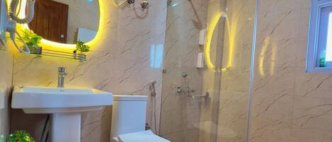 A modern bathroom with a glass-enclosed shower, a white sink, and a toilet.
