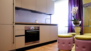 Een moderne keuken met een ingebouwde oven, een roestvrijstalen afzuigkap en een paars gordijn.