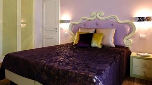 Een slaapkamer met een bed, nachtkastje, kledingkast en een wandlamp.