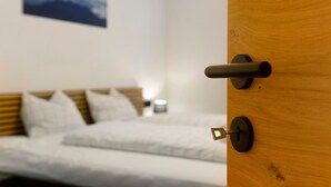A bedroom with a bed, a wooden door, and a wall-mounted picture.