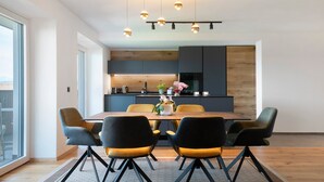 A modern dining area with a wooden table, black and yellow chairs, and pendant lighting.