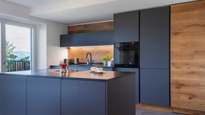 A modern kitchen with a central island, dark cabinetry, and a wooden accent wall.