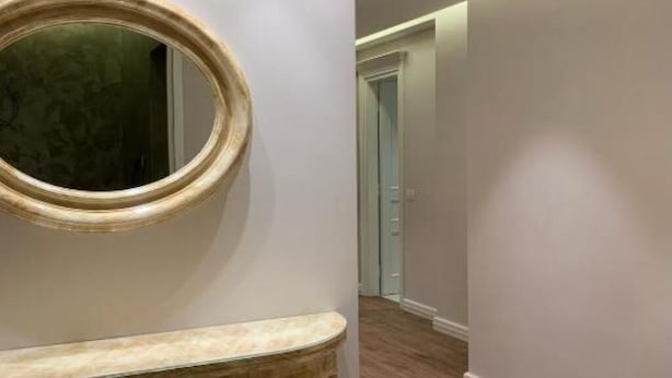 Une salle de bain avec un miroir rond, un banc en marbre et un plancher en bois.