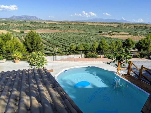 A swimming pool with a view of agricultural fields and mountains in the background.