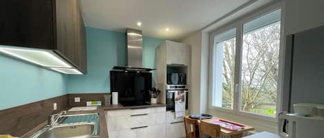 A modern kitchen with a built-in oven, microwave, and a large window providing a view of the outdoors.