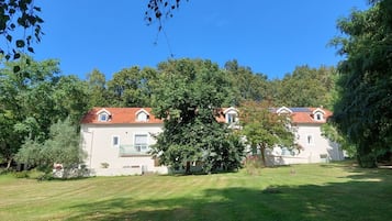 Un edificio con tejado de tejas rojas, rodeado de abundante vegetación y árboles.