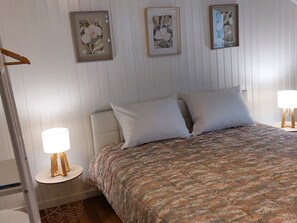 A bedroom with a bed, two bedside lamps, a wooden ladder, and three framed floral artworks on the wall. - Spacious cottage near natural sites and Puy du Fou (Cheffois)