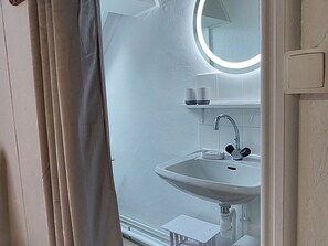 A bathroom with a white sink, a mirror, and a small shelf with cups. - Spacious cottage near natural sites and Puy du Fou (Cheffois)