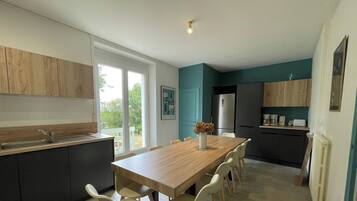 A modern kitchen with a dining table and chairs, a refrigerator, and a window providing a view of the outdoors.