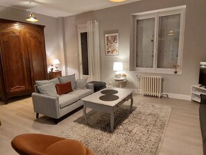 A living room with a sofa, a coffee table, a radiator, and a window.