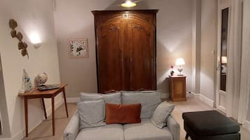 Una sala de estar con un sofá gris, un mueble de madera, una mesita con un globo terráqueo y una lámpara.