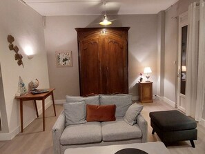 A living room with a grey sofa, a wooden cabinet, a small table with a globe, and a lamp.
