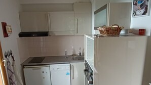 A compact kitchen with white cabinets, a dishwasher, a sink, and a refrigerator. - Spacious apartment in Super Besse with pool and parking (Besse-et-Saint-Anastaise-Super Besse)