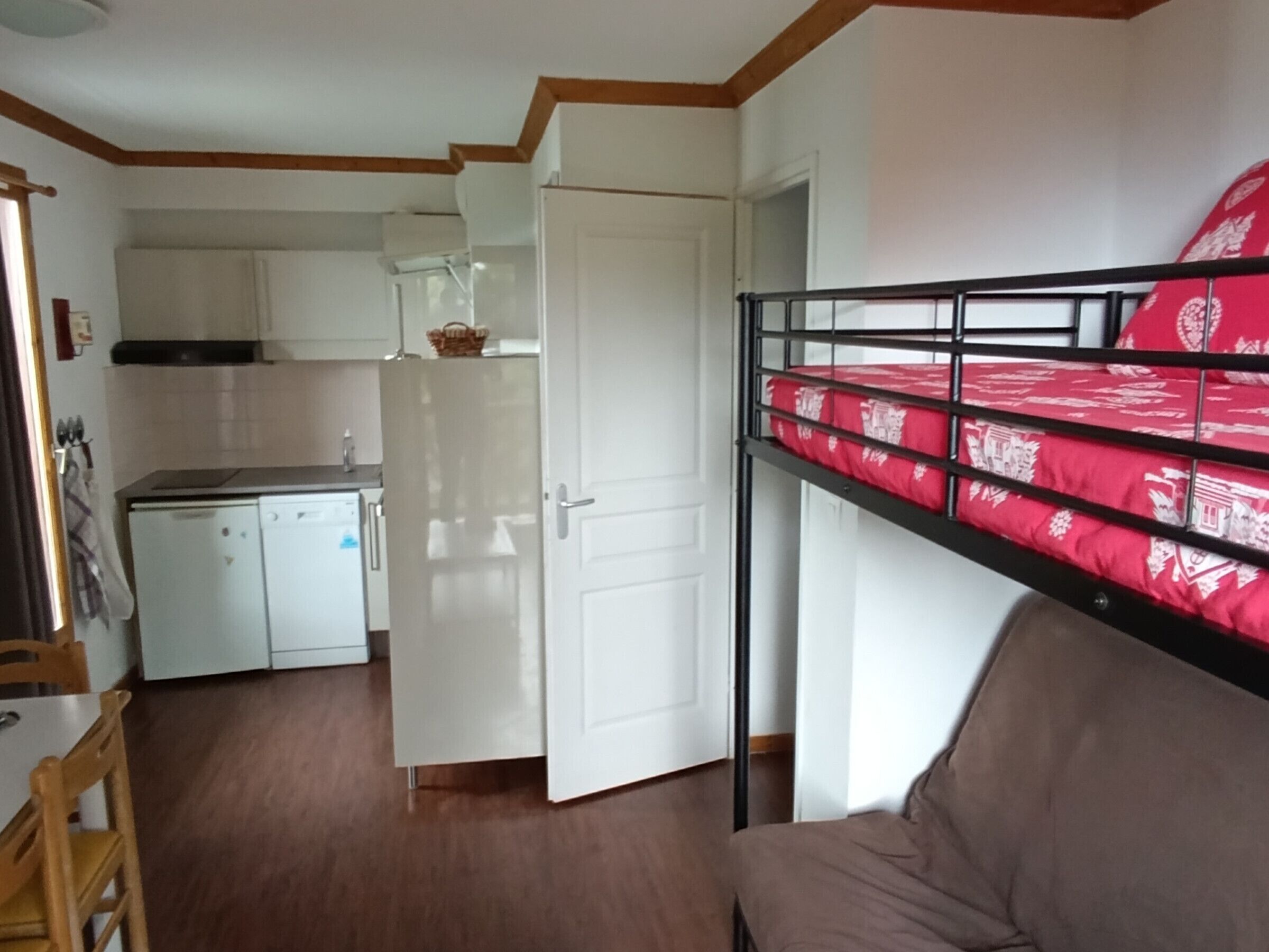 Une petite pièce comprenant un lit superposé, un coin cuisine et un espace repas.