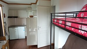 A compact room with a bunk bed, a kitchenette, and a dining area. - Spacious apartment in Super Besse with pool and parking (Besse-et-Saint-Anastaise-Super Besse)