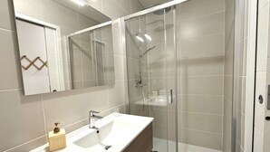 A modern bathroom with a glass-enclosed shower, a white sink with a soap dispenser, and a mirror above the sink. - Cozy apartment in Praz-sur-Arly with parking and balcony, near slopes, for 6 people (Praz-sur-Arly)