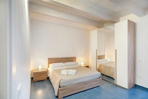 A bedroom with a bed, bedside tables, a mirror, and a wardrobe.