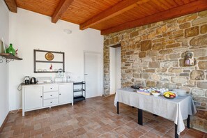 A kitchen with a stone wall, a white cabinet, and a table set with food.