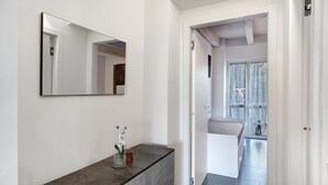 Un pasillo con un espejo, una consola de mármol y una cama visible a través de una puerta abierta.
