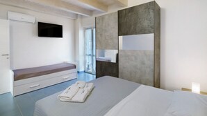 Un dormitorio moderno con una cama, un banco, un televisor y un espejo grande.