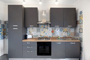A kitchen with grey cabinets, a wooden countertop, a built-in oven, and a tiled backsplash.