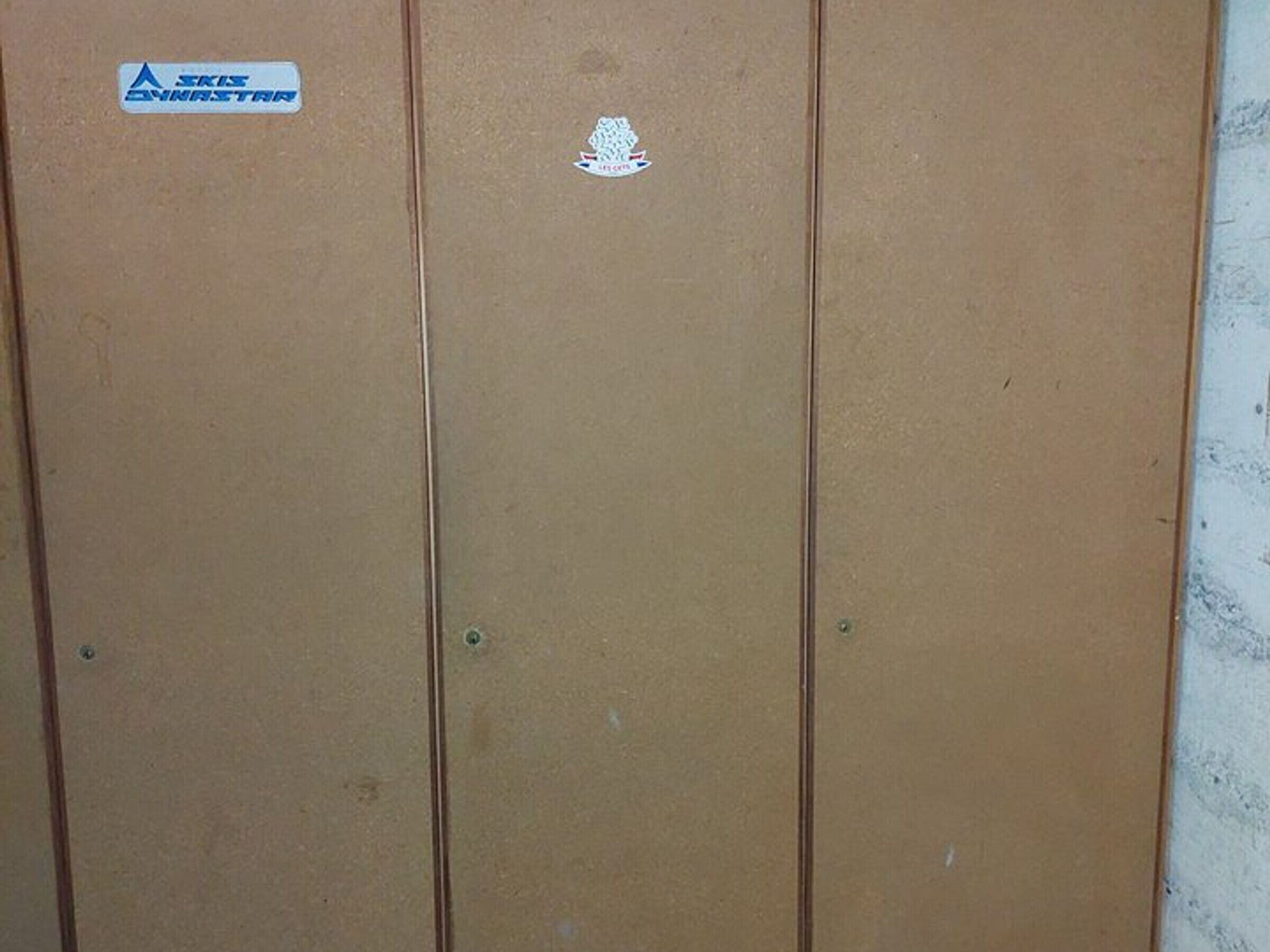 A brown door with a sticker that reads "SKIS" and another with a logo.