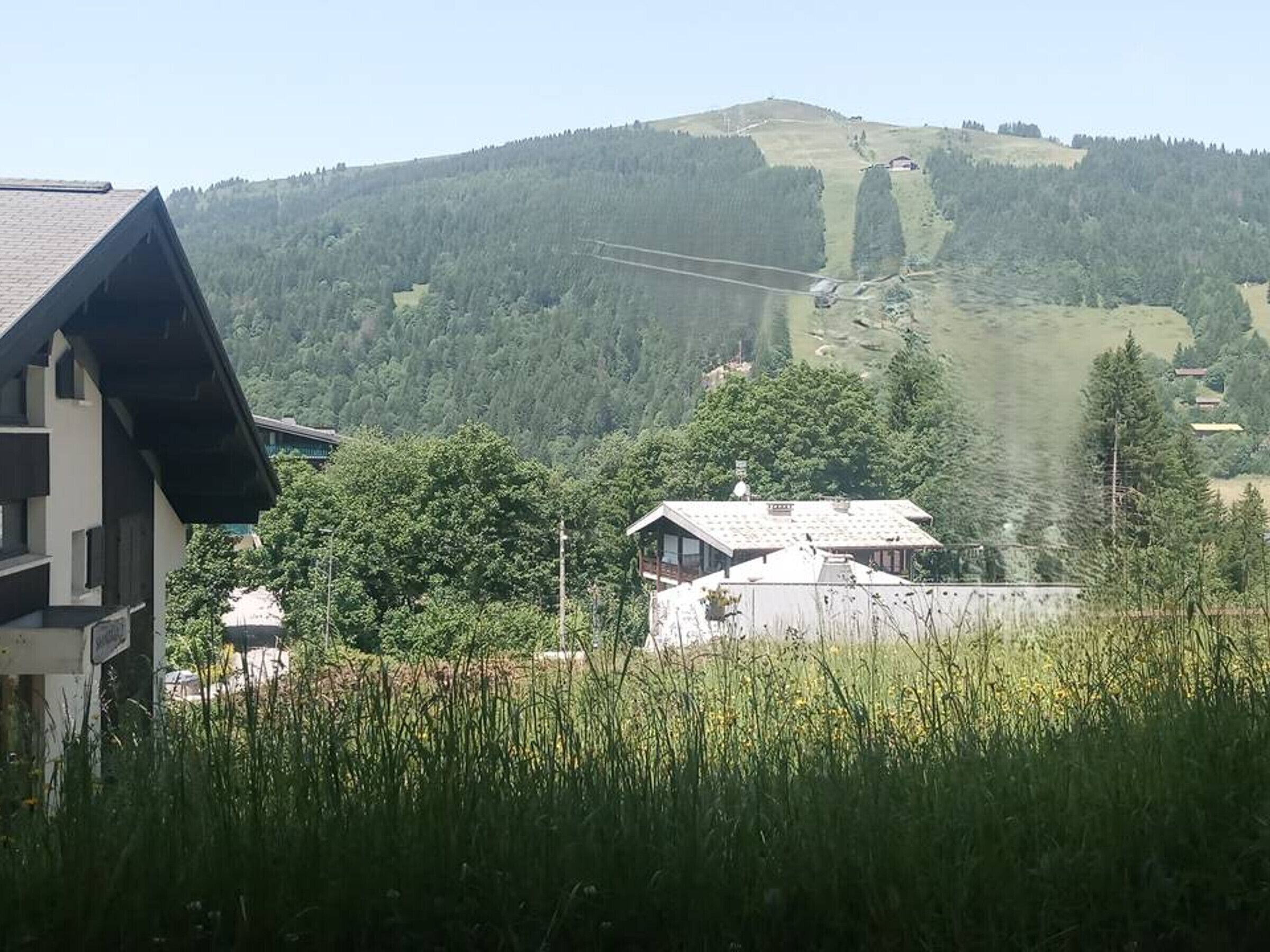 A mountain view with a house and a ski lift in the background.