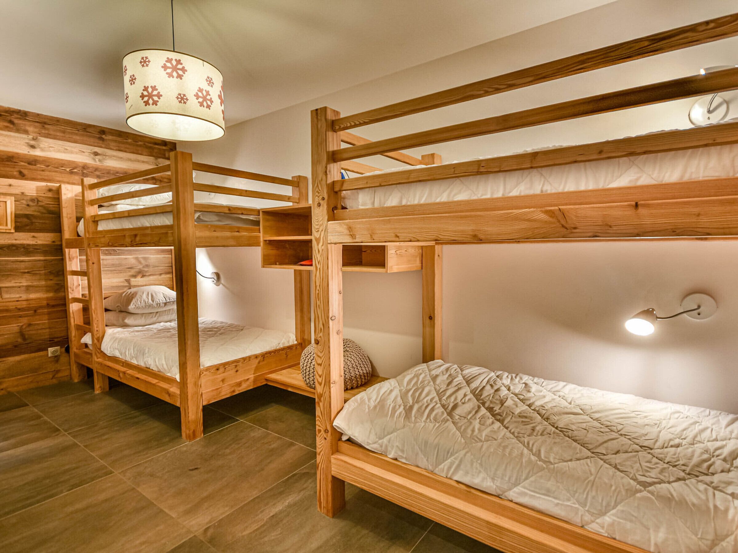 A room with bunk beds, wooden walls, and a hanging light fixture.
