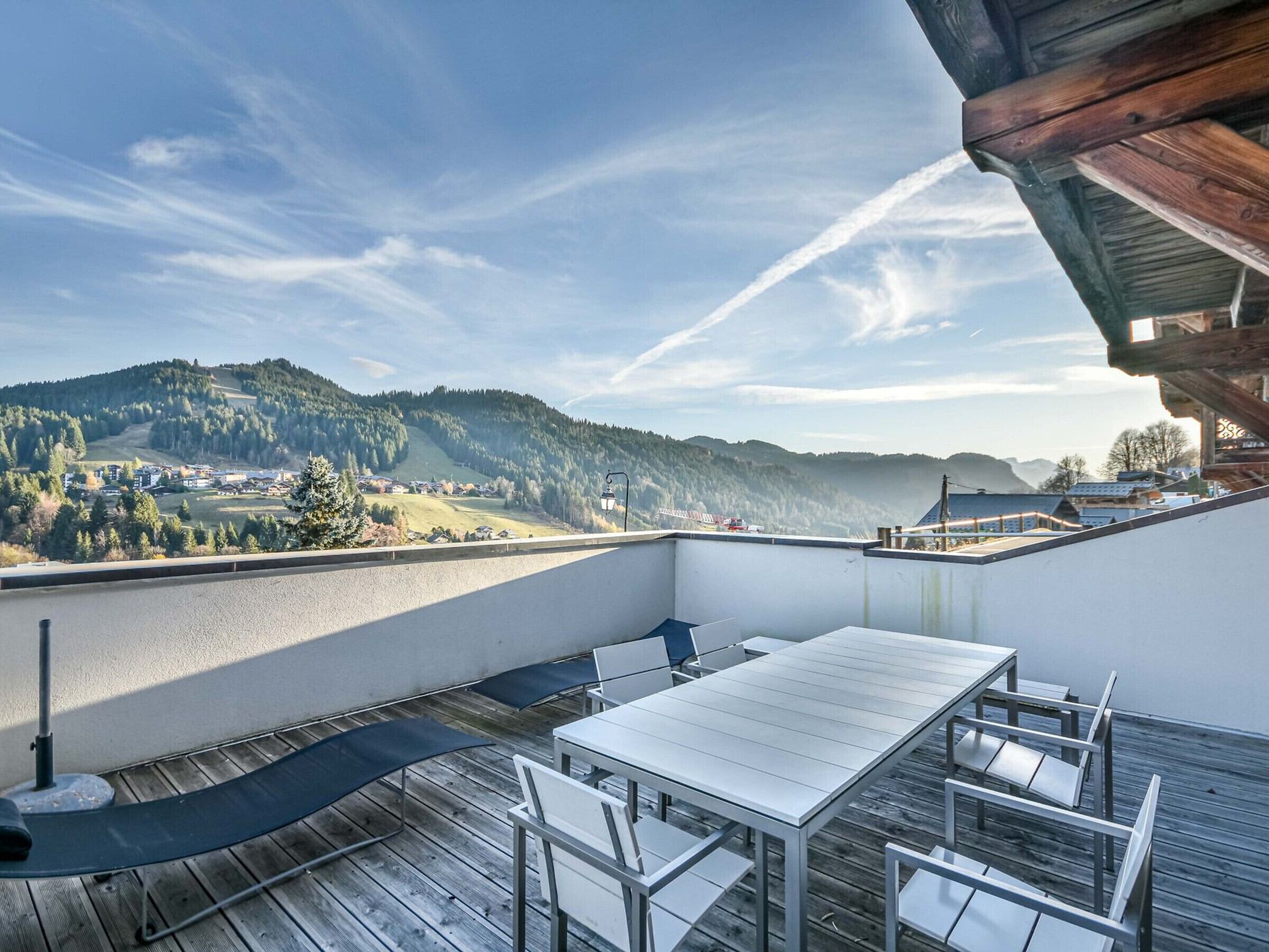 Un balcón con mesa y sillas, con vista a un paisaje montañoso.