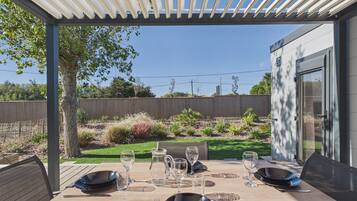 An outdoor dining area with a table set for four, surrounded by a wooden fence and a garden.