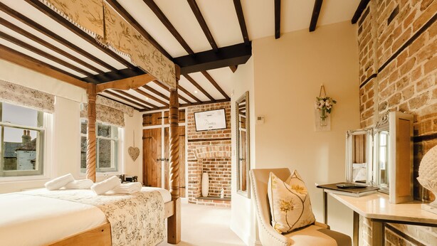 A bedroom with a large bed, a chair, a desk, and a fireplace. - Experience boutique comfort above The Powell pub in Birchington. Stylish en-suite rooms, luxury touches, and a vibrant pub below—perfect for business, couples, or families. Book your coastal escape today! (Birchington)
