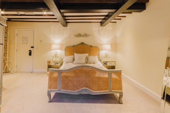 A bedroom with a large bed, two bedside tables with lamps, a door, and a mirror.