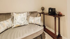 A living room with a sofa, pillows, a coffee table, and a wall-mounted thermostat.