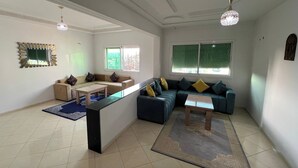 Un amplio salón con un conjunto de sofás, una mesa de centro y un televisor.