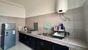Una cocina moderna con un refrigerador de acero inoxidable, una estufa a gas, un fregadero y un escurreplatos.
