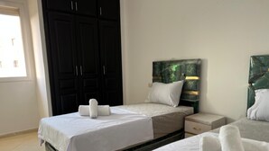 Una habitación de hotel con dos camas, una mesita de noche y un armario.