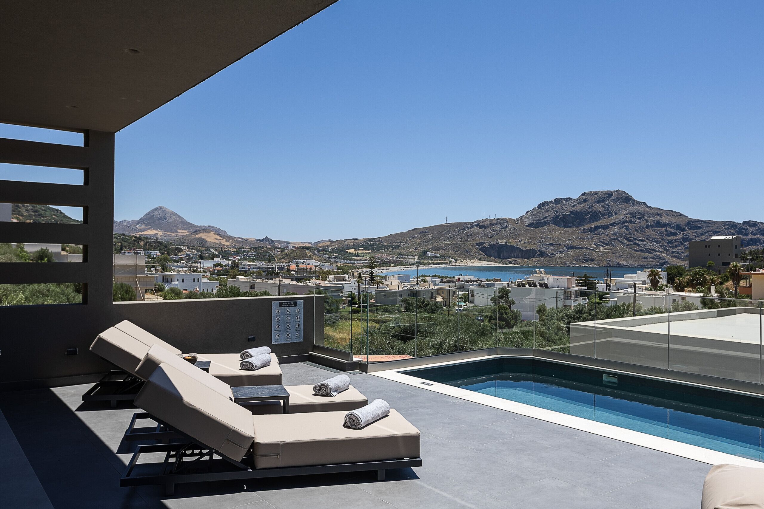 A rooftop pool area with lounge chairs and a view of a mountainous landscape.