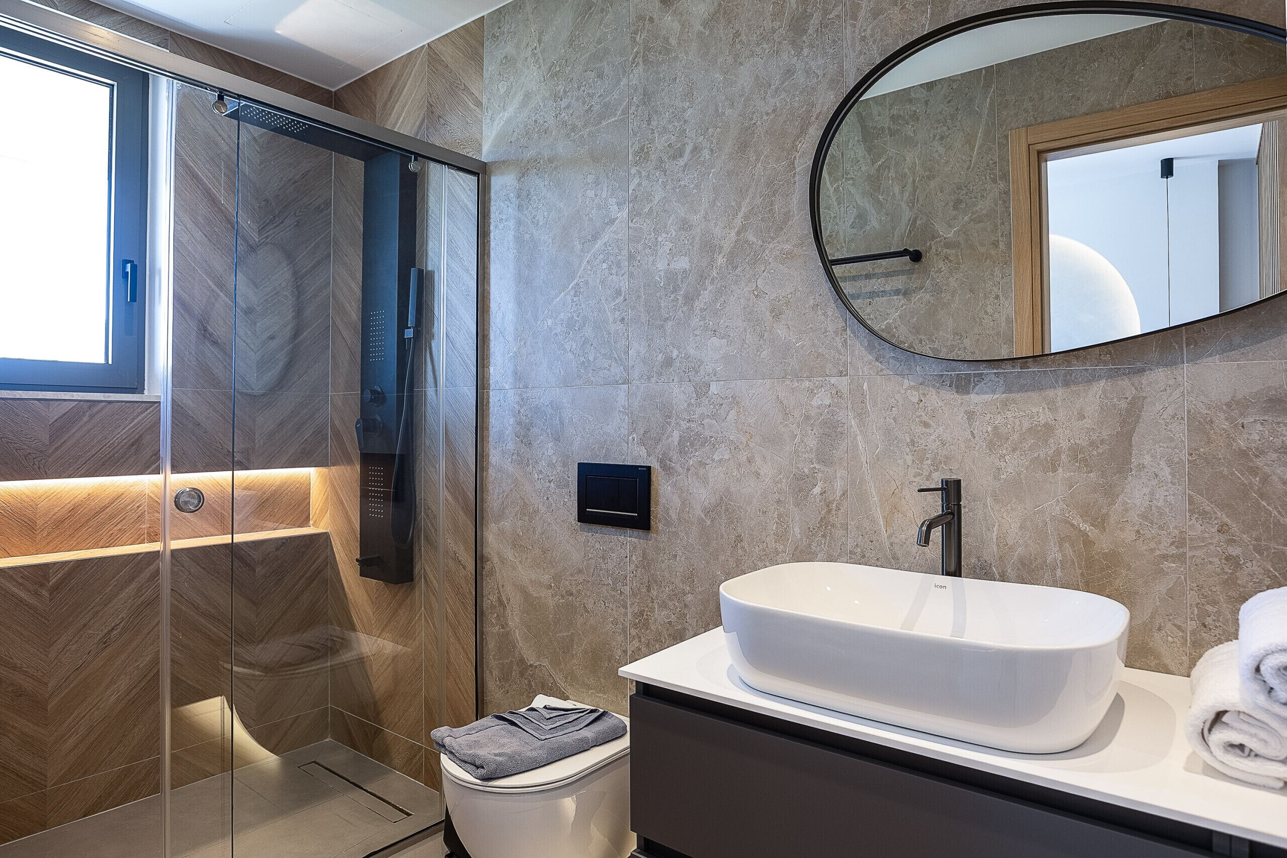 A modern bathroom with a glass-enclosed shower, a white sink, and a mirror.
