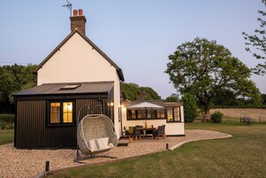 Une maison à l’extérieur blanc, avec une partie de la façade peinte en noir, et une terrasse comprenant une table et des chaises.
